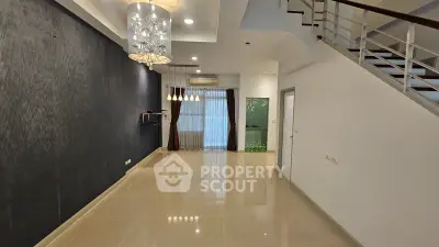 Spacious modern living room with elegant chandelier and large windows for natural light.