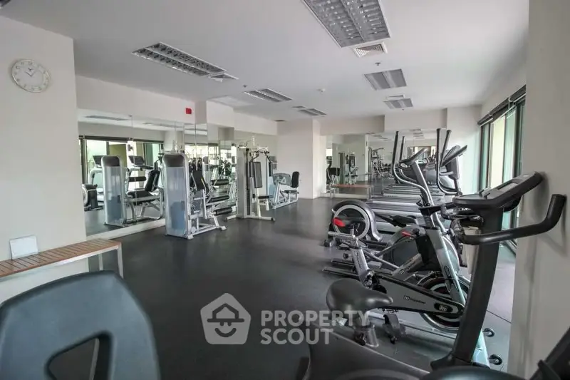Spacious modern gym with state-of-the-art fitness equipment and mirrored walls in a luxury residential building.