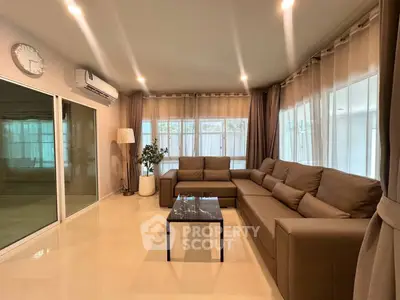 Spacious living room with modern brown sectional sofa and large windows for natural light.