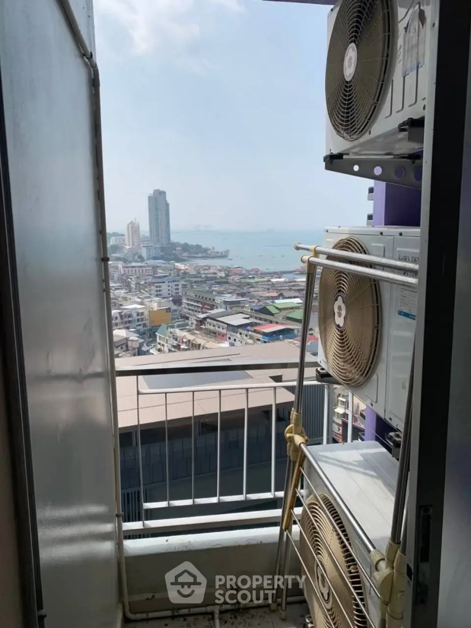 Stunning cityscape view from a high-rise balcony with air conditioning units.