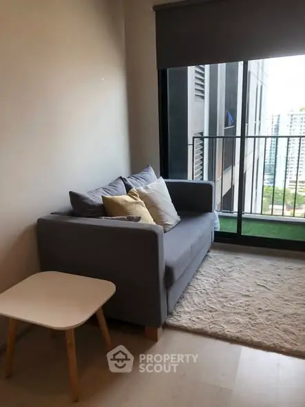 Cozy living room with a modern sofa and city view balcony in a high-rise apartment.