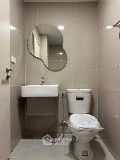 Modern bathroom with unique mirror and sleek fixtures in a contemporary apartment.