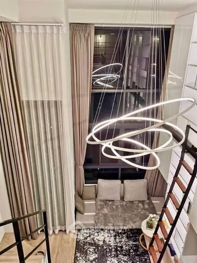 Modern loft interior with stylish lighting and large windows, featuring cozy seating and elegant decor.