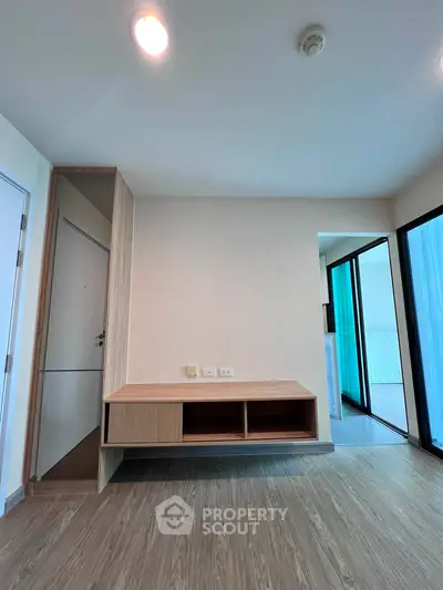 Modern living room with sleek wooden flooring and balcony access in a stylish apartment.