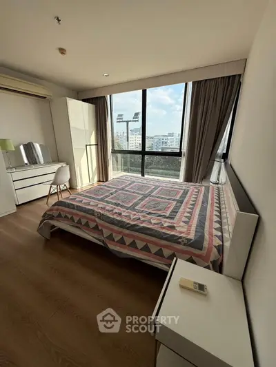 Spacious bedroom with large window and modern decor in urban apartment