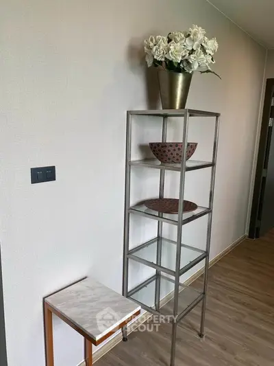 Modern interior with sleek metal shelf and decorative items in a stylish hallway.