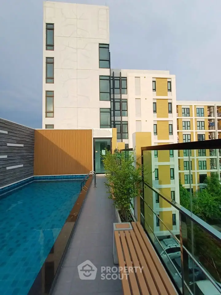 Modern apartment building with rooftop pool and glass railing, offering a luxurious urban lifestyle.