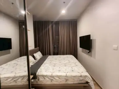 Modern bedroom with cozy bedding and wall-mounted TV in a stylish apartment.