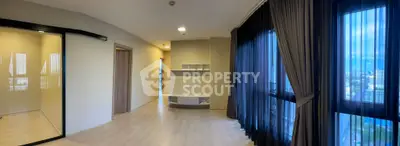 Spacious modern living room with large windows and elegant curtains offering stunning city views.