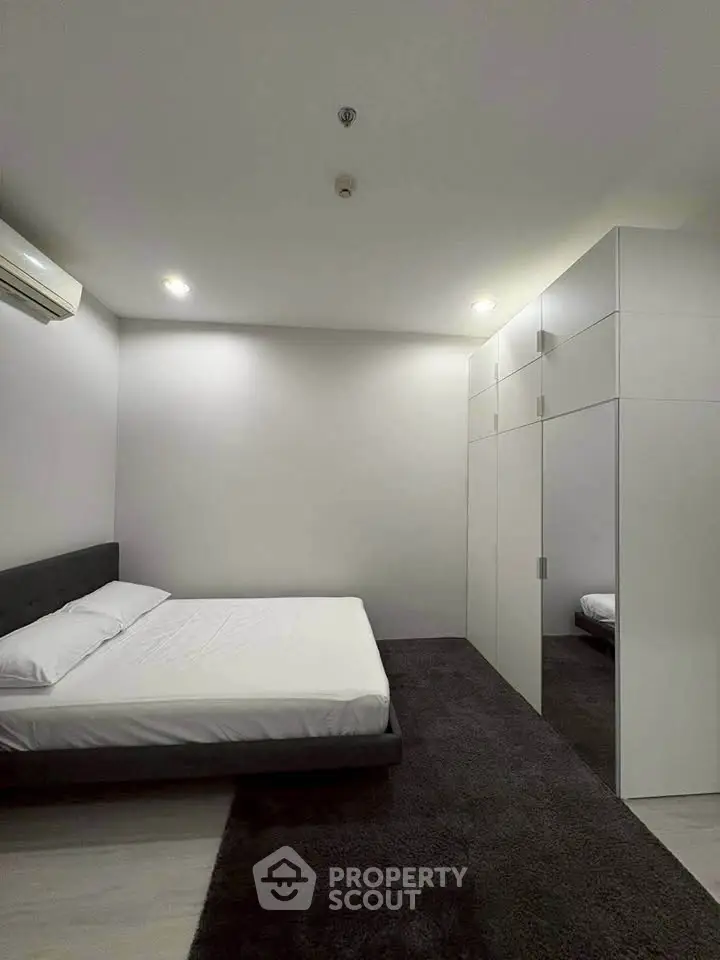 Modern minimalist bedroom with sleek design and ample storage space.