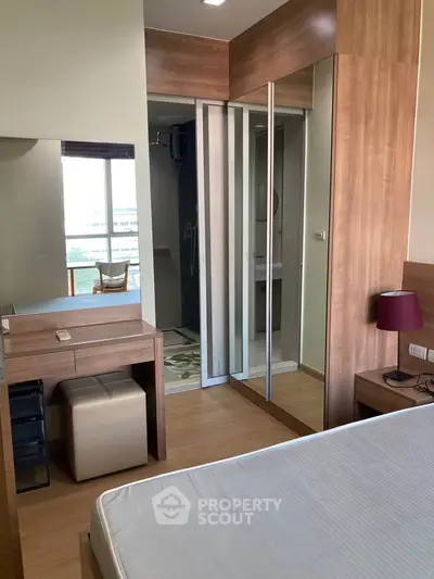 Modern bedroom with mirrored closet and wooden accents, featuring a cozy dressing area and natural light.