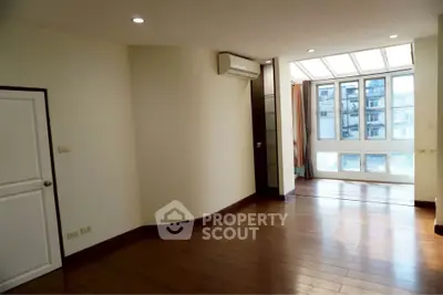 Spacious empty room with wooden flooring and large windows