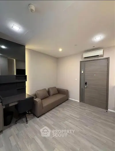 Modern living room with sleek sofa and workspace, featuring minimalist design and neutral tones.