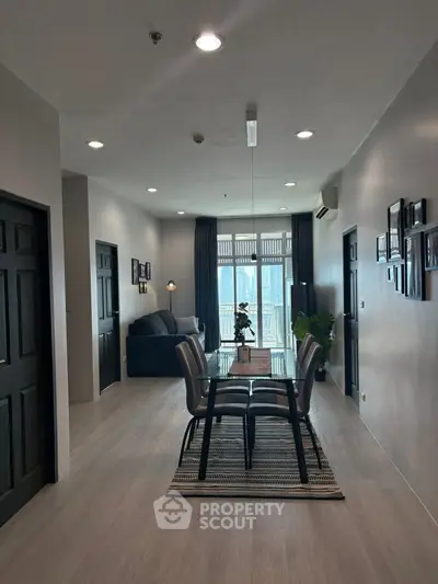 Modern dining area with sleek table and chairs, leading to a cozy living room with natural light.