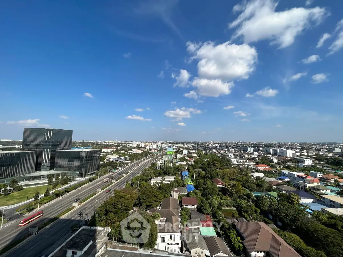 Stunning aerial view of urban landscape with modern buildings and lush greenery under a clear blue sky.