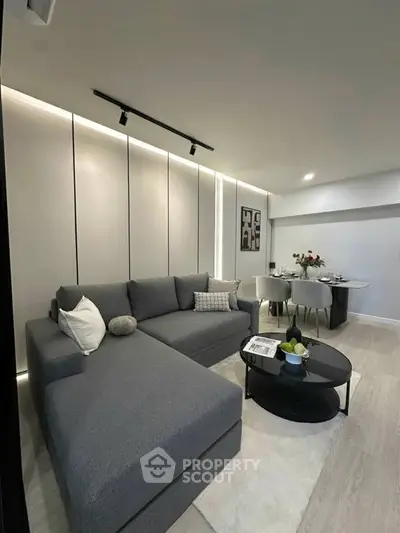 Modern living room with sleek gray sectional sofa and elegant dining area