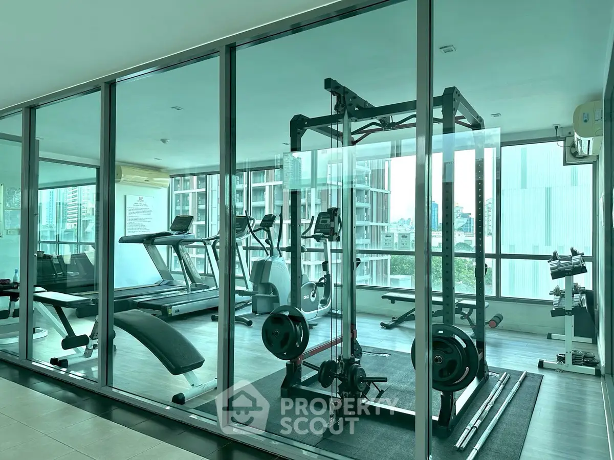 Modern gym with state-of-the-art equipment and city view in luxury apartment building.