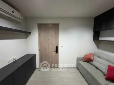 Modern living room with sleek furniture and air conditioning, featuring a cozy sofa and minimalist design.