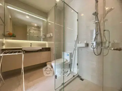 Modern bathroom with glass shower, sleek fixtures, and elegant lighting.
