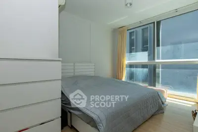 Bright and cozy bedroom with large window and modern furnishings.