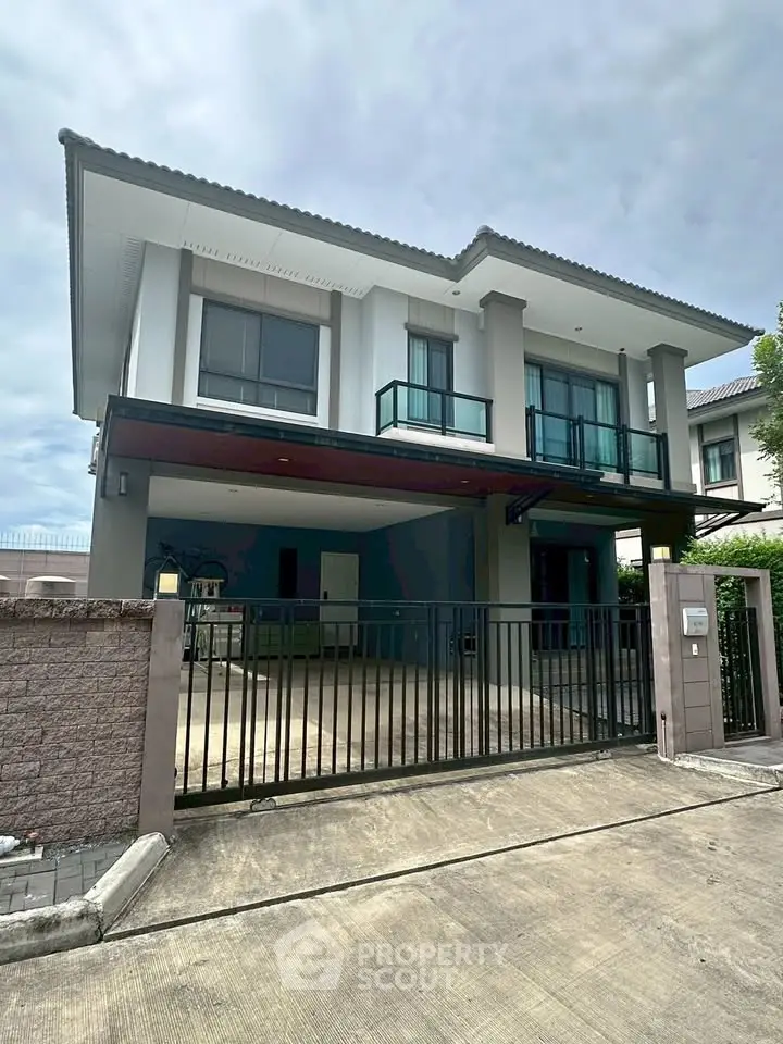 Modern two-story house with gated driveway and contemporary design.
