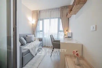 Modern living room with cozy sofa and stylish desk, featuring large window with elegant curtains.