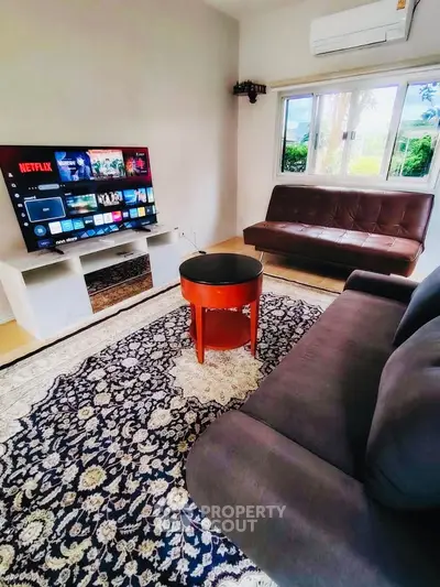 Cozy living room with modern furniture and large TV, perfect for relaxation.