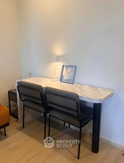Modern study area with sleek marble desk and stylish chairs in a cozy apartment setting.