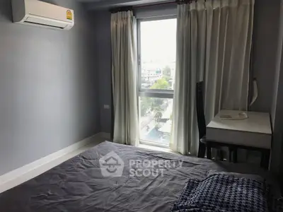 Cozy bedroom with large window and air conditioning, offering natural light and city view.