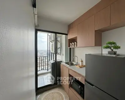 Modern kitchen with balcony view, sleek cabinetry, and compact design in urban apartment.