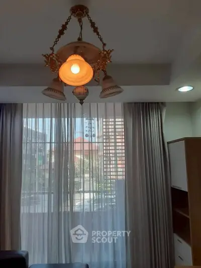 Elegant living room with classic chandelier and large window with curtains.