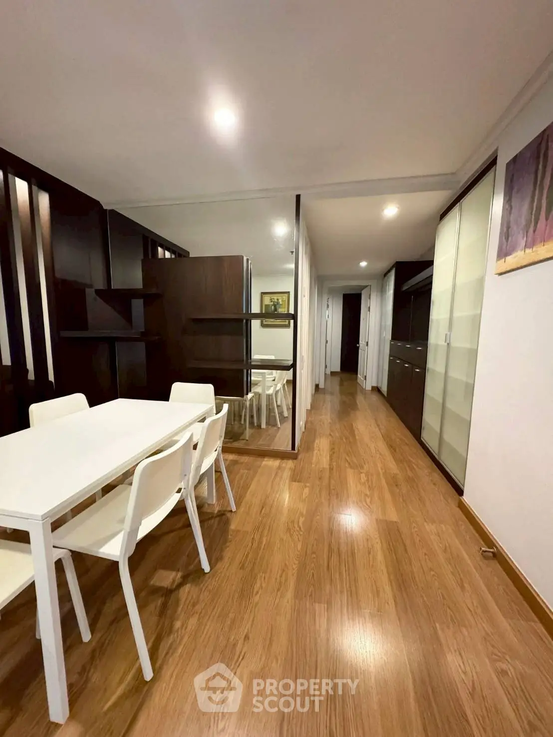 Modern dining area with sleek wooden flooring and contemporary furniture in a stylish apartment.