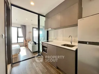 Modern open-layout kitchen with sleek cabinetry and adjacent living area in a stylish apartment.
