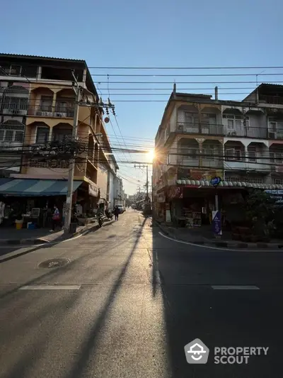 Charming urban street view with sunlight peeking through buildings, showcasing vibrant city life.