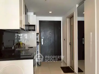 Modern kitchen with sleek black countertops and integrated appliances in a stylish apartment.