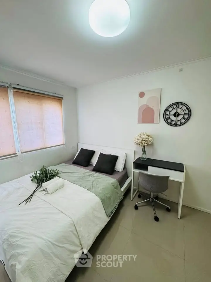 Cozy bedroom with modern decor, featuring a comfortable bed, stylish desk, and elegant wall clock.