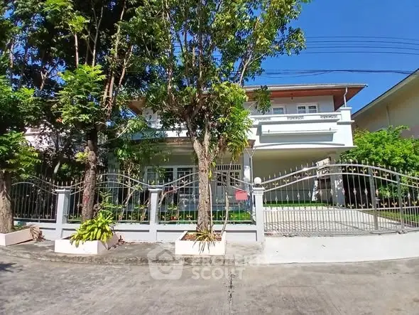 Charming two-story house with gated entrance and lush greenery
