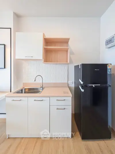 Modern kitchen with sleek cabinetry and black refrigerator in a stylish apartment.