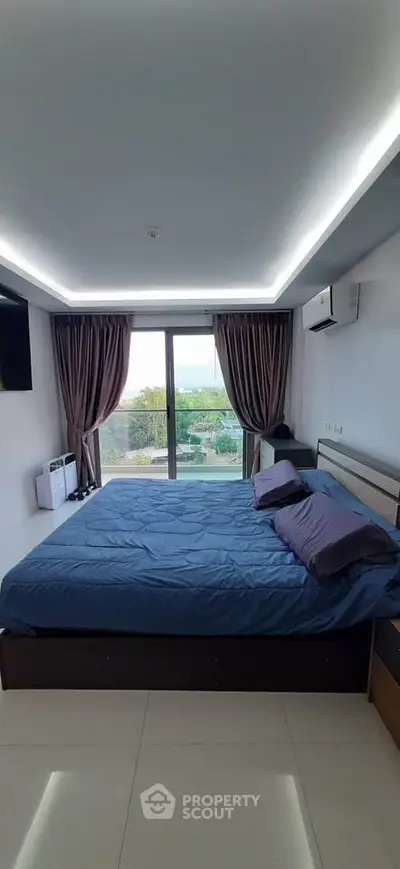 Spacious bedroom with large window offering stunning view, modern furnishings, and elegant lighting.