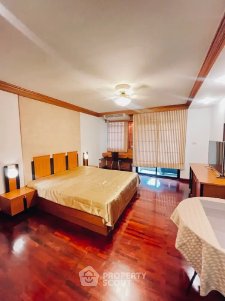 Spacious bedroom with wooden flooring and elegant decor in a modern apartment.