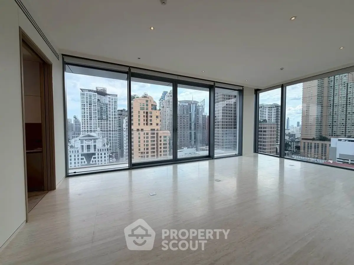 Spacious modern living room with floor-to-ceiling windows offering stunning city views.