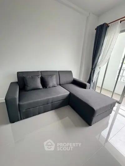 Modern living room with sleek gray sectional sofa and floor-to-ceiling windows.