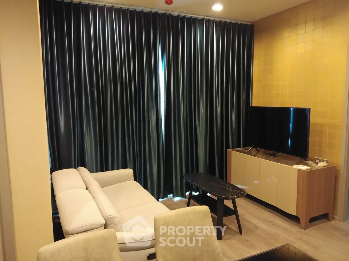 Modern living room with elegant sofa, sleek TV stand, and stylish curtains in a cozy apartment.
