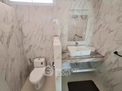 Modern bathroom with marble walls and sleek fixtures in a contemporary home.