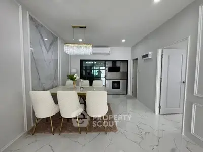 Elegant dining area with modern chandelier and marble flooring in a stylish open-plan layout.