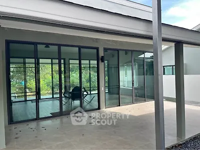 Modern home with large glass doors opening to a spacious patio and lush greenery.