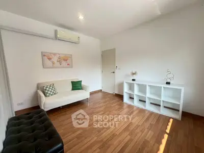 Spacious living room with modern decor and wooden flooring, featuring a cozy sofa and stylish shelving unit.