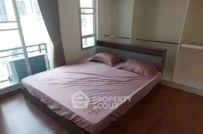 Cozy bedroom with large window and wooden flooring, perfect for natural light lovers.