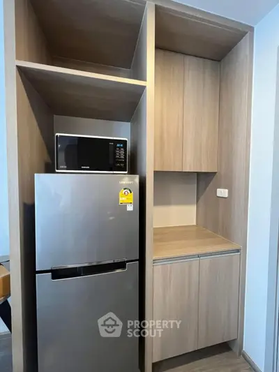 Modern kitchen with sleek fridge and microwave in stylish wooden cabinetry.