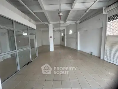 Spacious commercial space with tiled flooring and glass partition, ideal for retail or office use.